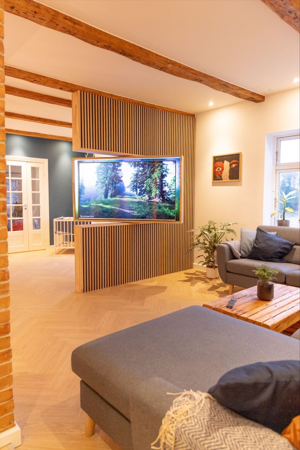 Modern living room with large television and wooden accents.