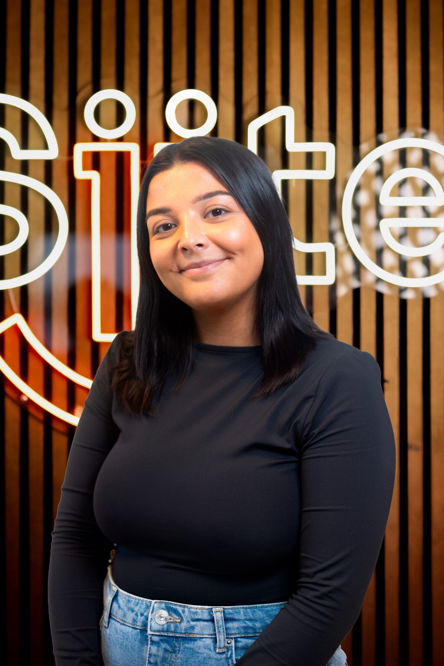 Woman smiling in front of lit sign